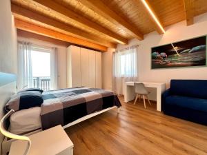 a bedroom with a bed and a desk and a couch at Sogno Blu - Levico in Levico Terme