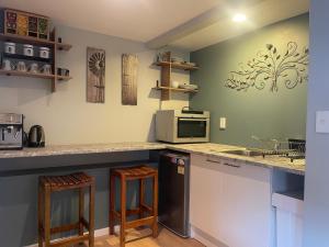 a kitchen with a microwave and a counter with stools at Cove side Bliss in Whangaparaoa
