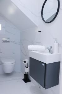a white bathroom with a sink and a mirror at Duplex terrasse vue mer et ville, Pieds dans l'eau in Monastir
