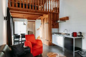 a living room with a red chair and a kitchen at Hotel & Lodges Erve Bruggert in Haaksbergen