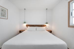 a white bed in a white bedroom with two lamps at El Rincón House Tenerife Tijoco in Adeje +20 photos