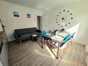 a living room with a table and a couch at Le pont T3 étoilé 2 chambres in Saint-Méloir-des-Ondes