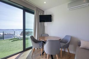 una sala da pranzo con tavolo e sedie e una grande finestra di Complejo Bungalow con piscina a A Pobra do Caramiñal