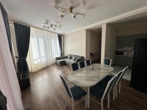 a dining room with a table and chairs and a couch at Антей Большой in Koshkolʼ