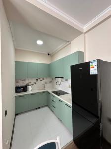 a kitchen with green cabinets and a black refrigerator at Антей Большой in Koshkolʼ +2 photos