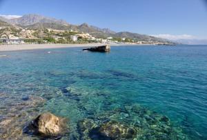 a view of a beach with crystal clear water at colored houses in Ierapetra