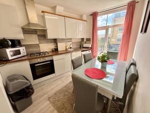a kitchen with a table with chairs and a window at Enormous Family Flat (7 guests) in London