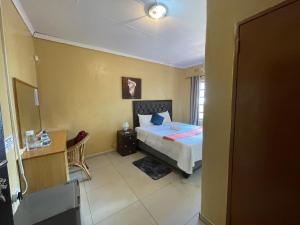 een slaapkamer met een bed en een bureau in een kamer bij Ntshe River Lodge in Francistown