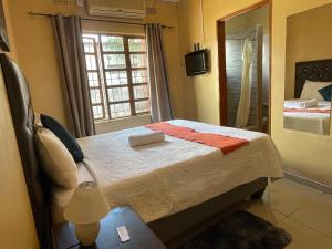 een slaapkamer met een bed en een raam met een televisie bij Ntshe River Lodge in Francistown