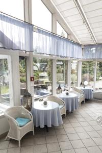 een restaurant met witte tafels, stoelen en ramen bij Hotel Paradiesquelle 4 in Puchberg am Schneeberg