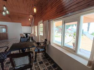 a living room with windows and a table and chairs at Maharanee Bungalow Darjeeling in Darjeeling