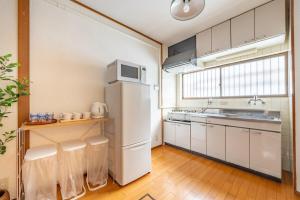 a kitchen with a white refrigerator and a microwave at GUEST HOUSE Hotori 2nd in Otsu