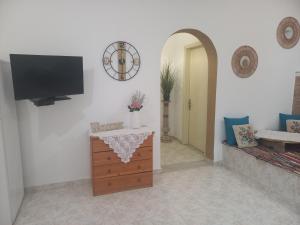 a living room with a tv on a white wall at Maria's garden house in Archangelos