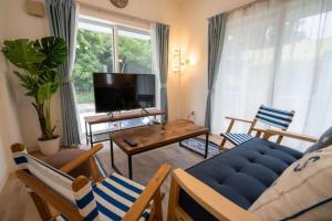 ein Wohnzimmer mit einem blauen Sofa und Stühlen in der Unterkunft 家族の笑顔 希望ヶ丘ビーチまで徒歩5分でのんびり家族ステイ Coral Onnason in Onna