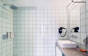 a white tiled bathroom with a sink and a shower at Hotel Brummell in Barcelona