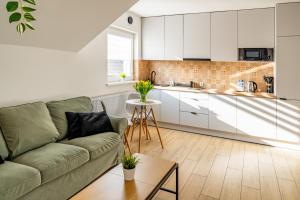 a living room with a couch and a kitchen at NT Holiday Apartament in Dźwirzyno