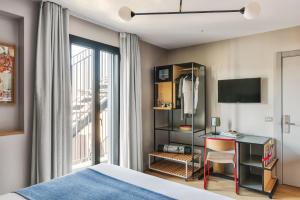 a bedroom with a bed and a desk and a window at Hotel Brummell in Barcelona