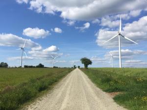 a dirt road in a field with wind turbines at Gîte du Bois Brillant in Couffé +12 photos