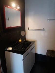 a bathroom with a black sink and a mirror at Casa da Prainha 4 in São Caetano