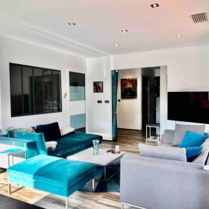 a living room with blue couches and a tv at Villa Miroir d'O in Gujan-Mestras