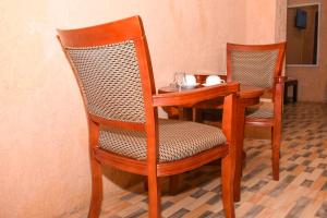a wooden table with two chairs and a table with a bowl at Best Point Hotel Zanzibar in Mwana Kerekwe