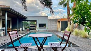 a patio with a table and chairs next to a swimming pool at Villa Miroir d'O in Gujan-Mestras
