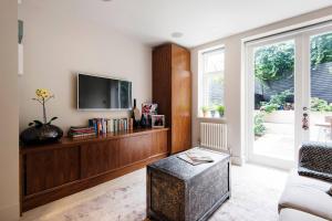 a living room with a tv and a ottoman at The Bohemian Rhapsody, Hampstead - by Out of office Lifestyle in London +43 photos