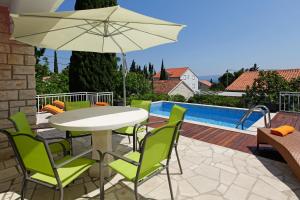 a patio with a table and chairs and an umbrella at Vacation Home Villa Oleandra in Bol