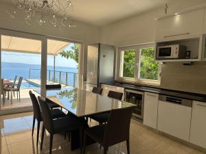 a kitchen with a dining table and a view of the ocean at Villa Maranata-5 stars-pool-spa-gym-free parking-privacy in Jesenice