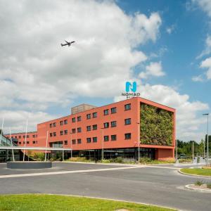 a large building with a plane on top of it at Nomad Paris Roissy CDG in Le Mesnil-Amelot
