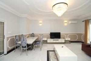 a living room with a table and chairs and a television at RAP Appart 302 avec piscine in Douala