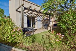 une maison blanche avec un banc dans la cour dans l'établissement Zéphyr, à Saint-Christol