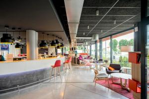 a restaurant with chairs and tables and a bar at Nomad Paris Roissy CDG in Le Mesnil-Amelot