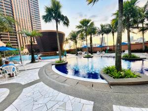 a large swimming pool with palm trees and buildings at Better Residence Suite at Times Square KL in Kuala Lumpur