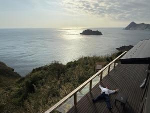 a man standing on a balcony looking at the ocean at IZU Elysian View in Koura