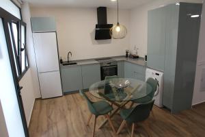 a kitchen with a glass table and green chairs at Ruzafa Acquamarina in Valencia