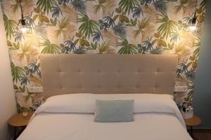 a bedroom with a white bed with a tropical wallpaper at Ruzafa Acquamarina in Valencia