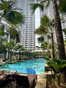 a swimming pool with palm trees and a tall building at Premium Taman Anggrek Residences in Jakarta