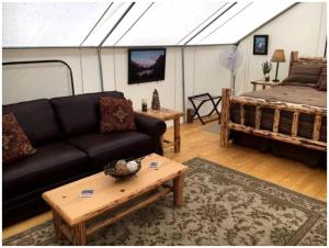 a living room with a couch and a bed at Gorgeous Luxury Tent Rental near Glacier National Park in Montana in Outback Mobile Home Settlement