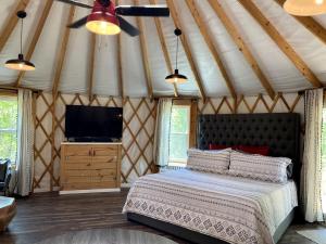 a bedroom with a bed and a tv in a tent at Serenity Yurt in Sunny View