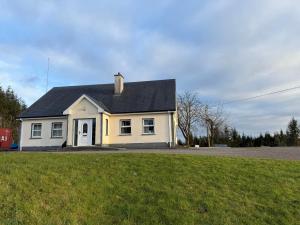 a white house with a black roof on a grass field at #1 - Family or Triple Room in Ballinamore, Leitrim in Ballinamore