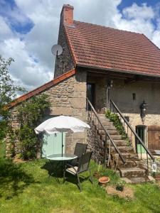 a table with an umbrella in front of a house at Bruyère en Fleur in Clugnat