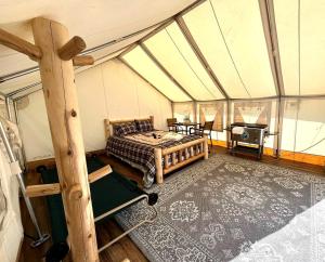 Cute and Comfortable Safari Tent in Seward, Alaska - Amazing Glamping Accommodation with Breathtaking Mountain Views في Bear Creek: غرفة بسرير وطاولة في خيمة