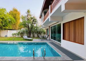 a swimming pool in front of a house at 提供免费汽车使用的含泳池被墅房间 in Chiang Mai
