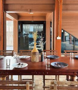 a wooden table with plates and a vase on it at 提供免费汽车使用的含泳池被墅房间 in Chiang Mai