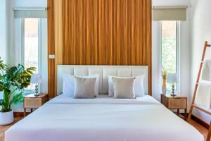 a bedroom with a large white bed with two windows at 提供免费汽车使用的含泳池被墅房间 in Chiang Mai
