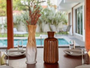 a table with a wooden vase and a bottle on it at 提供免费汽车使用的含泳池被墅房间 in Chiang Mai