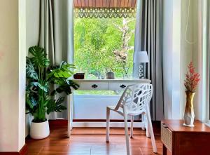 a desk with a chair in front of a window at 提供免费汽车使用的含泳池被墅房间 in Chiang Mai