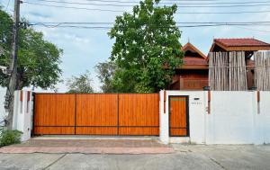 a house with a wooden gate and a white fence at 提供免费汽车使用的含泳池被墅房间 in Chiang Mai