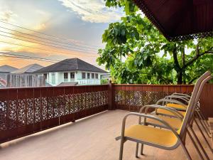 a balcony with chairs and a view of a house at 提供免费汽车使用的含泳池被墅房间 in Chiang Mai